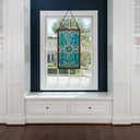 26"H Tiffany Style Stained Glass Brandi's Window Panel, suspended by a black cord in a bright room with white built-in shelves and a dark navy blue accent wall.