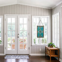 26"H Tiffany Style Stained Glass Brandi's Window Panel, suspended in a bright entryway with white paneled walls, glass doors, and a wooden side table.