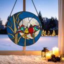 16"H Birds in the Night Sky Round Stained Glass Window Panel hanging in a window with a snowy landscape outside.