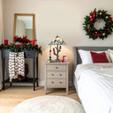 23.75"H Triple-Lit Stained Glass Cardinal Lamp on an end table in a bedroom decorated for the holidays