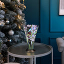 13.5" H Tiffany-Style Floral Vase Stained Glass Hurricane Table Lamp on a table next to a Christmas tree against a blue wall.