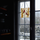 14"H Eden Red Cardinals in Autumn Stained Glass Window Panel hanging in a window with a snowy landscape outside
