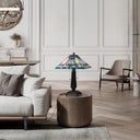 21" H Clarion Tiffany-Style Stained Glass Empire Shade Candlestick Base Table Lamp, set on a round wooden side table in a modern, elegant living room.