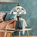 Tula 24.75" H Tiffany-style Blue Bowl Shade Stained Glass Table Lamp on a side table against a teal wall.