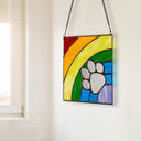 7" H Rainbow Paw Print Tiffany-Style Stained Glass Window Panel, hanging on a white wall.