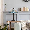 21" H Amberly Tiffany-Style Stained Glass Empire Shade Candlestick Table Lamp sits on a wooden side table in a styled living room setting next to a sofa with patterned pillows.