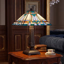 21" H Clarion Tiffany-Style Stained Glass Empire Shade Candlestick Base Table Lamp, set on a wooden side table in a classic living room next to a blue sofa and a teacup.