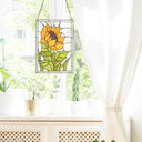 11.25”H Multicolored Sunflower Stained Glass Window Panel hanging on a window with plants below
