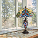 24" H Margaret Double Lit Amber Tiffany Style Stained Glass Table Lamp on a wooden surface with a window in the background