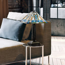 21" H Amberly Tiffany-Style Stained Glass Empire Shade Candlestick Table Lamp sits on a small round side table next to a brown upholstered sofa with white pillows in a modern living room setting.