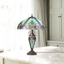 24.5" H Halston Double Lit Teal Bowl Shade Stained Glass Table Lamp on a marble surface in front of a draped window and cabinet